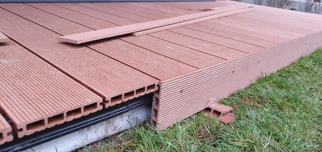 Tablas compuestas de núcleo hueco con listón de remate instaladas durante la construcción de una terraza exterior.