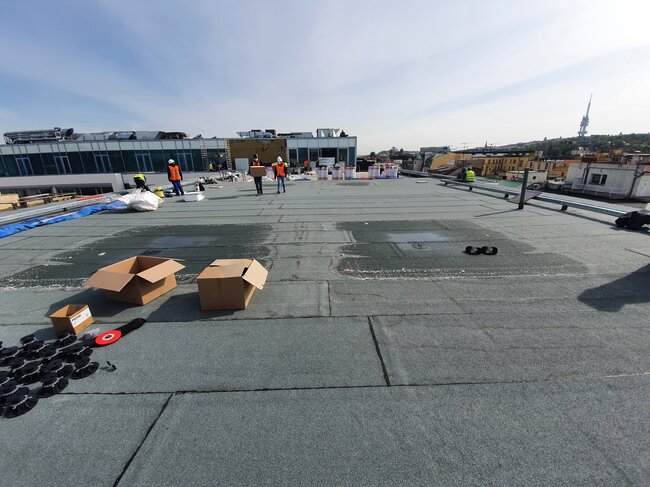 Construction workers preparing a flat roof membrane for paver installation.