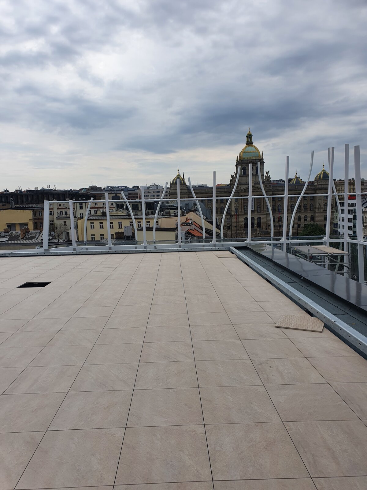 Terraza en la azotea con baldosas de porcelana exteriores instaladas y vistas a edificios urbanos históricos.