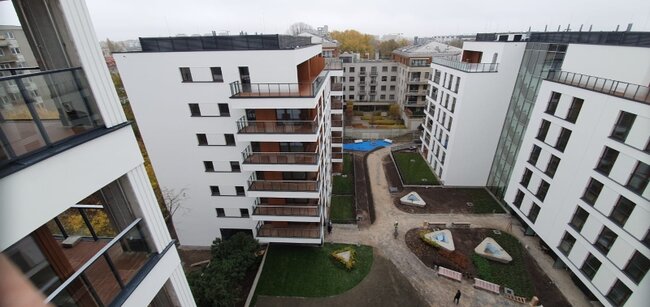 Vista aérea desde ángulo alto de un moderno complejo residencial con balcones y patios ajardinados.