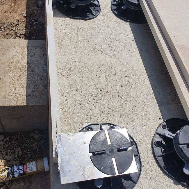 Sistema de soportes regulables para el apoyo de baldosas instalado sobre una base de hormigón.