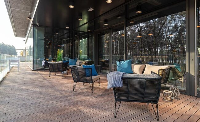 Muebles de salón modernos de exterior dispuestos sobre una terraza elevada de madera limpia.