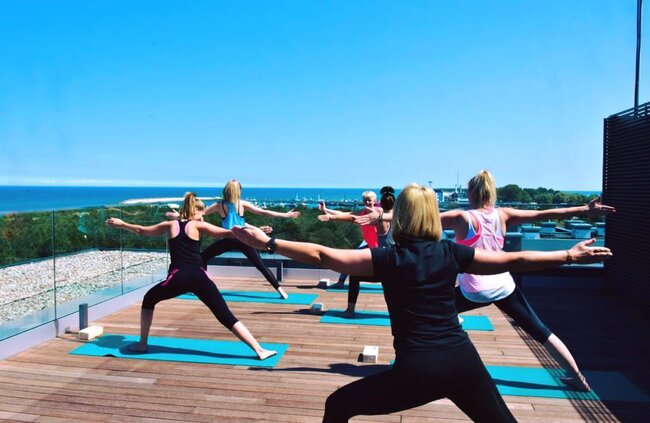 Terraza en azotea construida con plots soporte regulables que acoge una clase de yoga al aire libre.