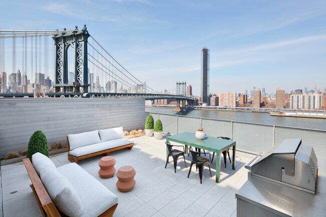 Terraza en la azotea con muebles de exterior, una parrilla y vistas al Puente de Manhattan y al panorama de Nueva York.