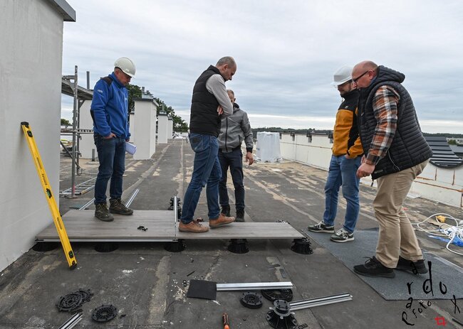 Ingenieros inspeccionando la instalación de baldosas en una terraza elevada en una azotea.