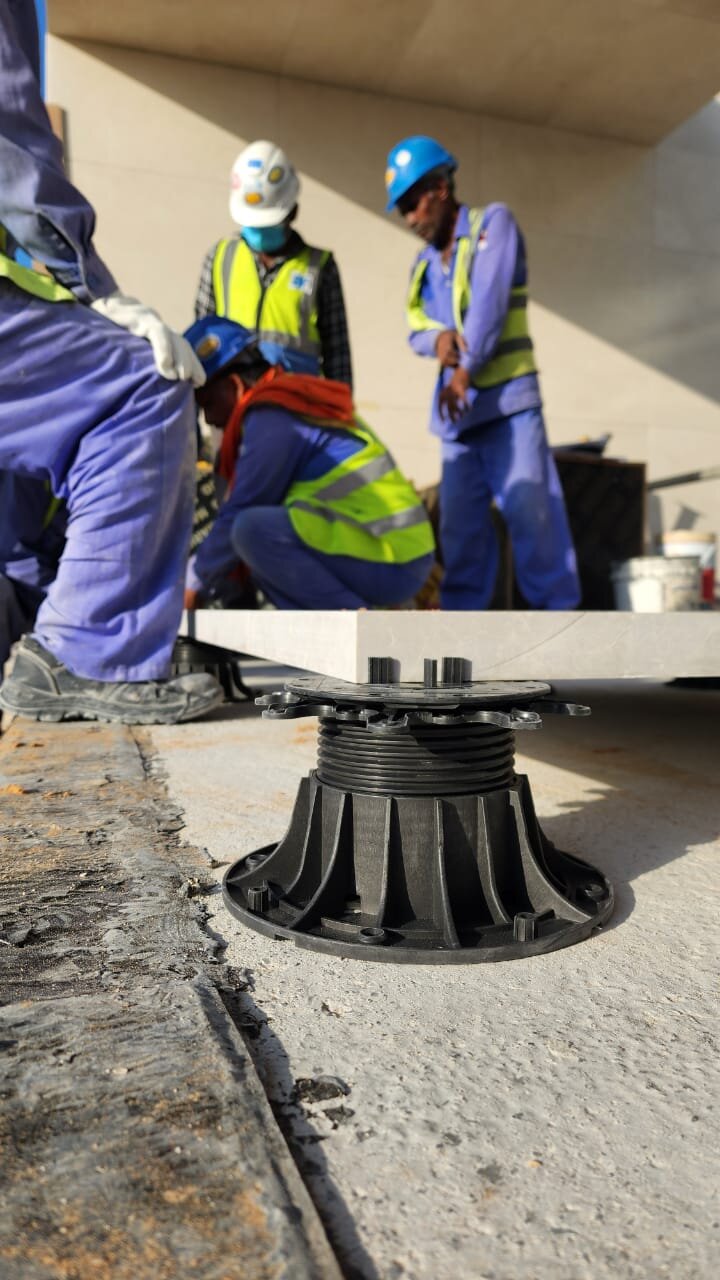 Sistema de soporte de plots de plástico regulables para baldosas elevadas en exteriores.