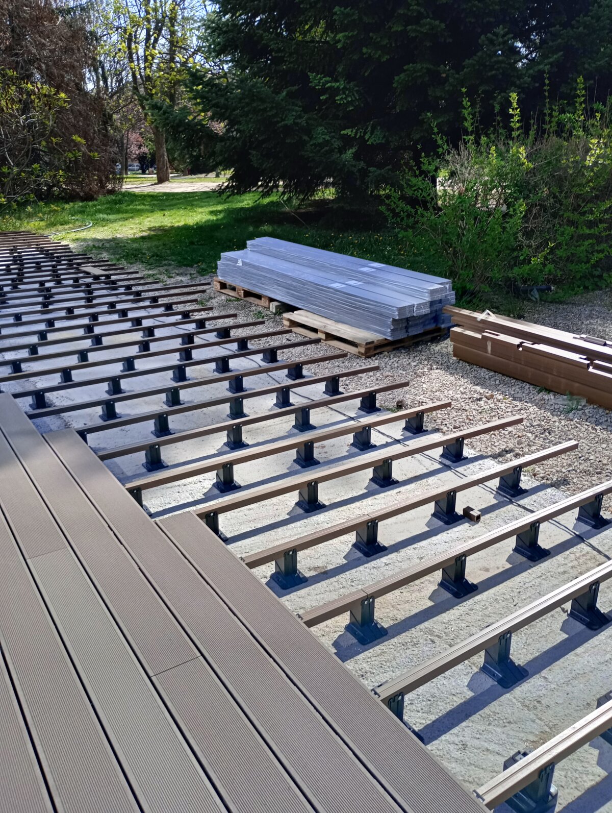 Tablas de composite para terraza instaladas sobre vigas de aluminio apoyadas en soportes regulables.