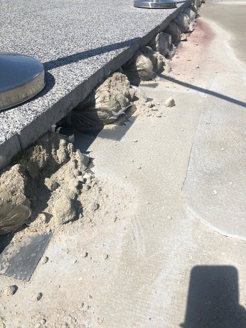 Baldosas de granito de terraza apoyadas sobre sacos de mortero debajo a lo largo del borde exterior.