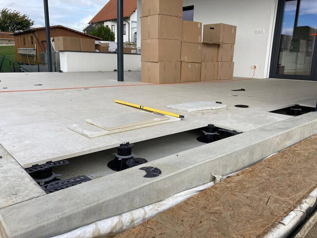 Instalación de baldosas en una terraza elevada utilizando soportes regulables en un patio exterior.