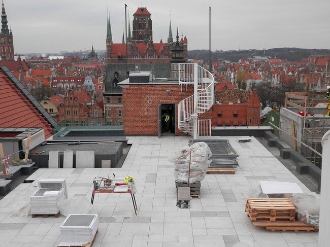 Terraza en la azotea en construcción con superficie elevada de baldosas sobre plots soporte regulables.