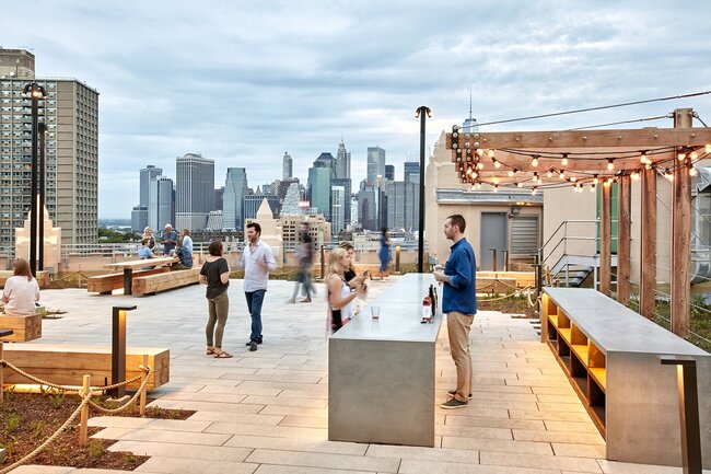 Terraza moderna en azotea con baldosas de piedra elevadas apoyadas sobre plots soporte regulables.