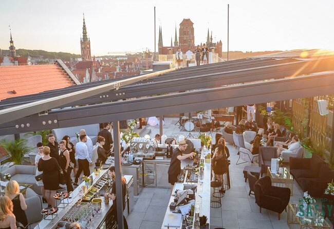 Terraza comercial en la azotea construida sobre un sistema de plots soporte regulables durante un evento al atardecer.