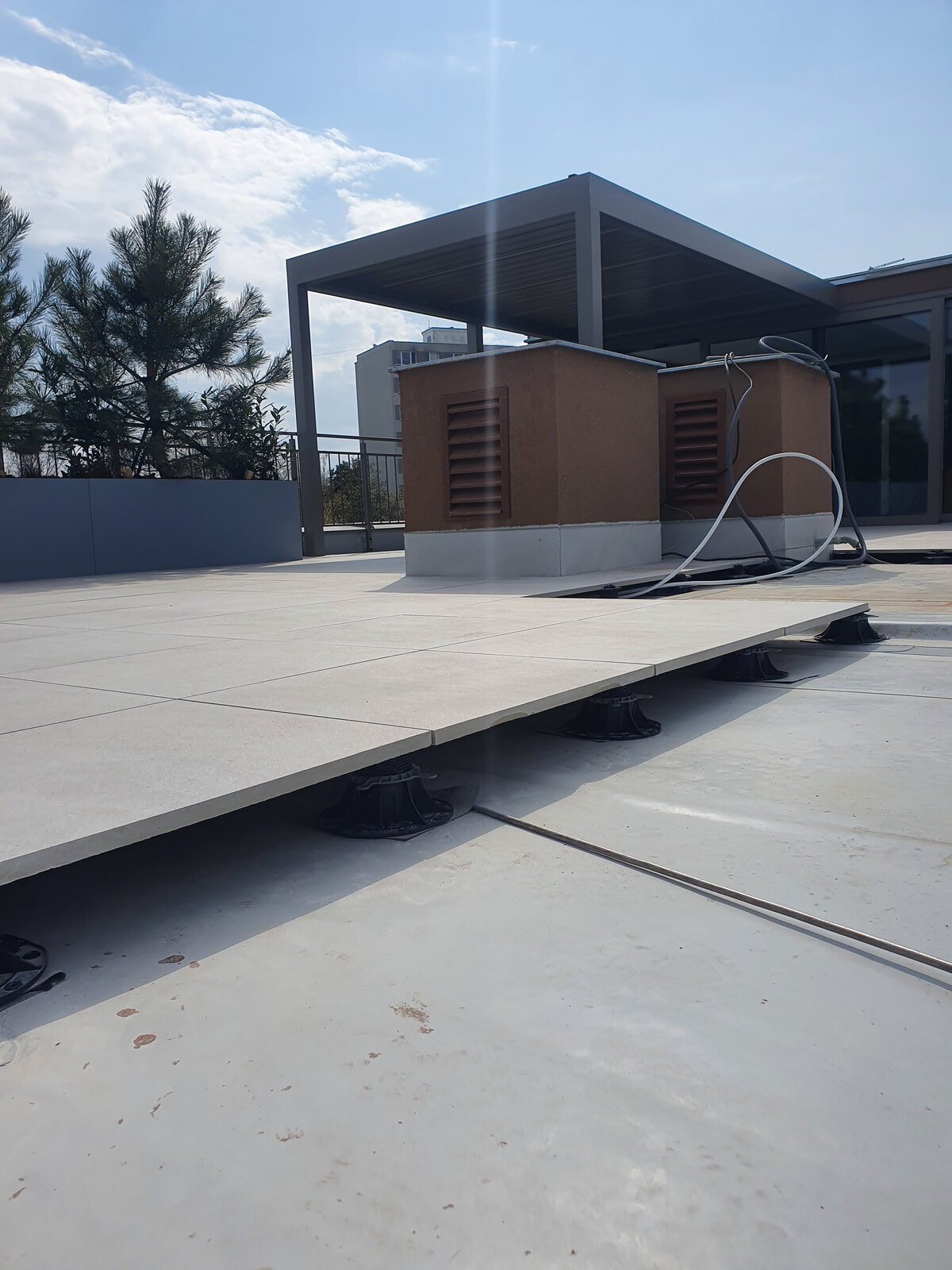 Sistema de plots soporte regulables que sostiene baldosas de terraza elevadas en el exterior.