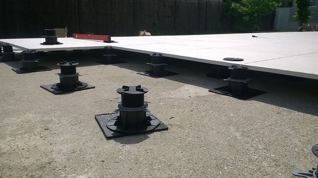 Montaje de una terraza elevada con plots soporte regulables para el apoyo de grandes baldosas de porcelana.