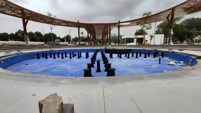Soportes regulables montados sobre el vaso de una fuente alicatado en azul en un sistema de suelo elevado para instalación de agua exterior.