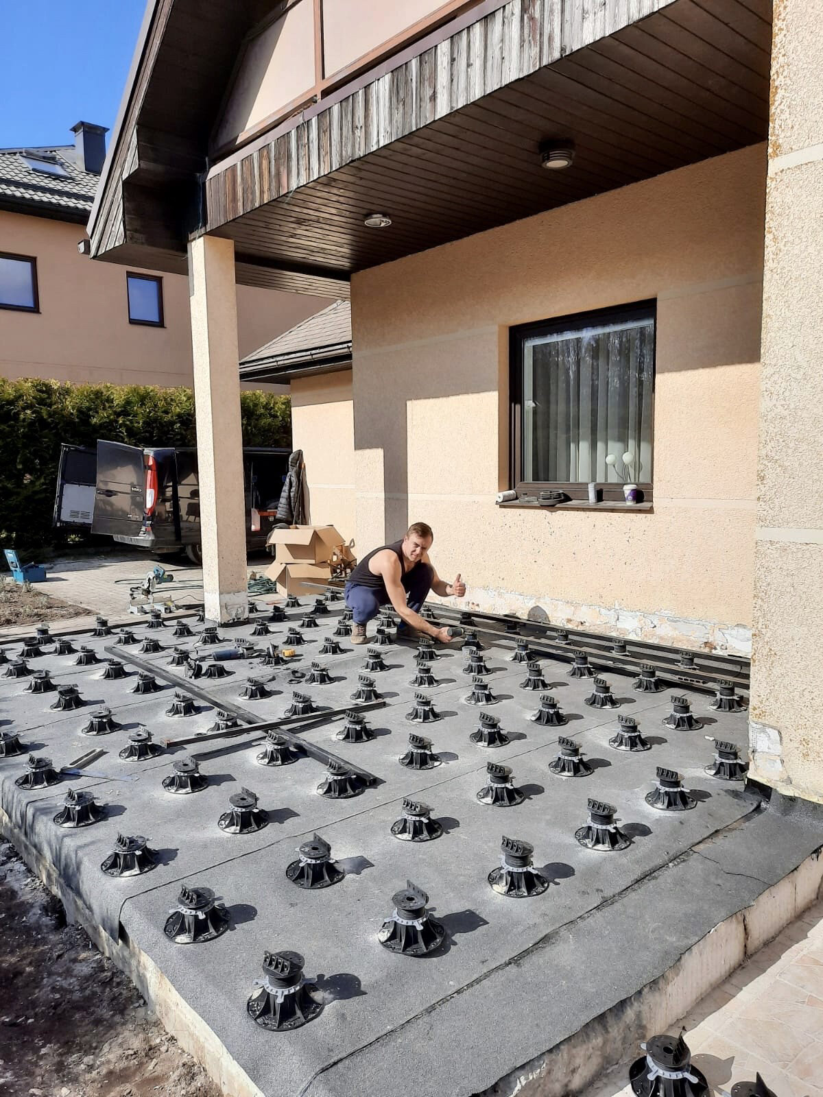 Trabajador nivelando plots soporte regulables para construir la estructura de vigas para el montaje de tablas compuestas.