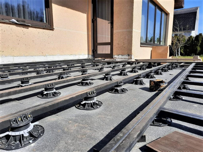 Plots Soporte Regulables de Terraza que soportan una subestructura metálica de vigas para la instalación de tablas compuestas.