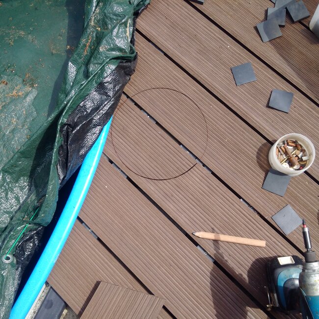 Marking and cutting composite decking boards around pool edges on an adjustable pedestal system.