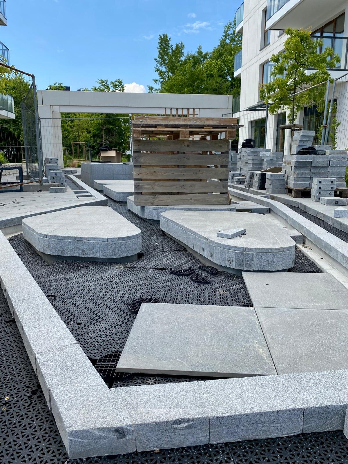 Paneles de subsuelo de drenaje encajables DeckSafe instalándose bajo baldosas de piedra en un proyecto de patio exterior.